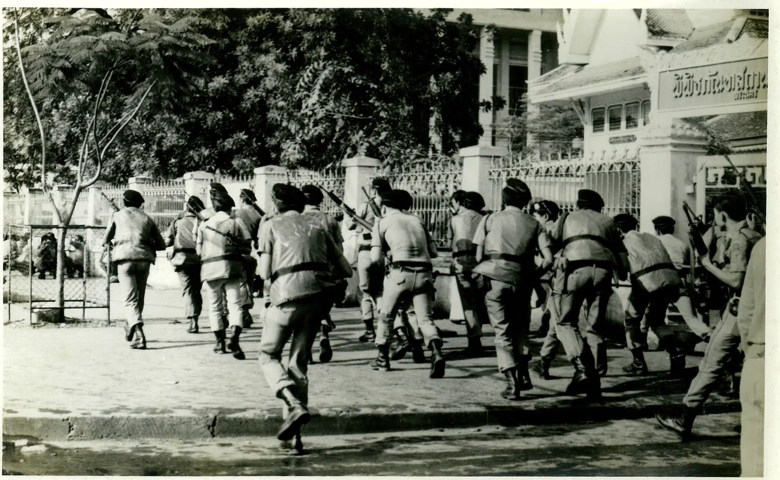 Uniformed police run crouching past the gate of the National Museum.